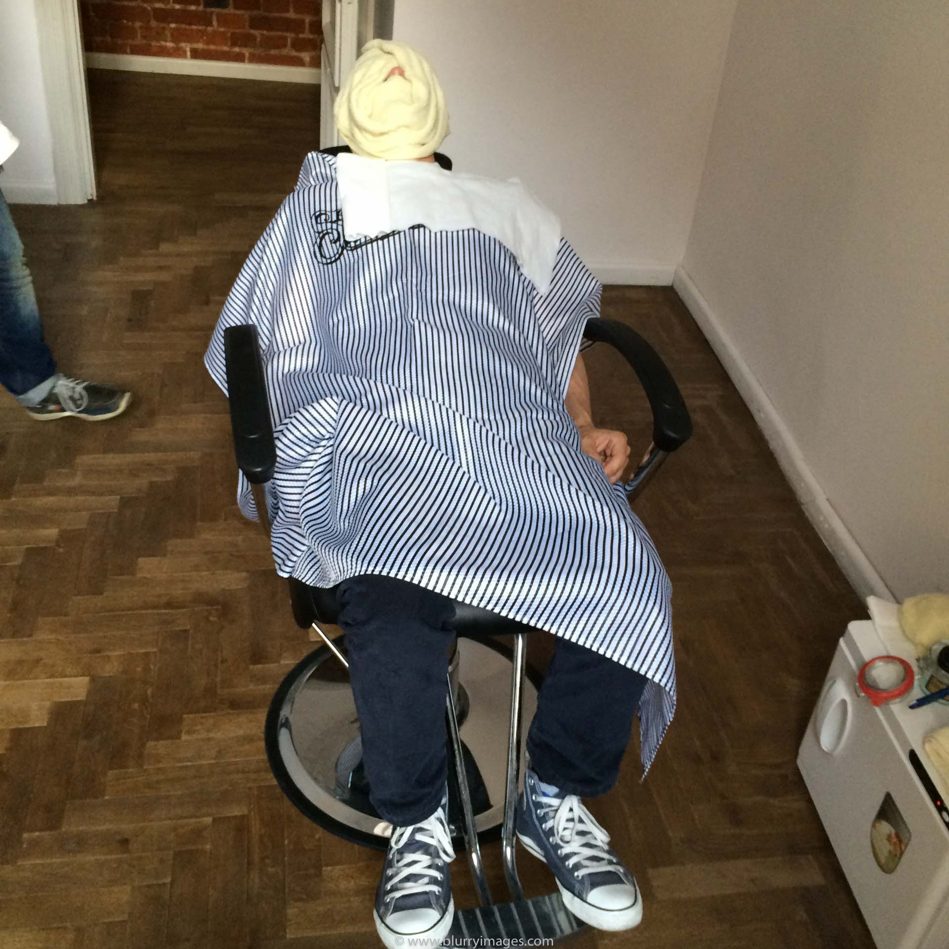 male barber, beard, trimmer, beard grooming, barber shop, adults only, Business Finance and Industry, hairdresser, wooden floor, armchair, yellow towel, white cupboard, white towel, man lies, blue jeans, blue shoes, white shoe-laces, indoors, 2015