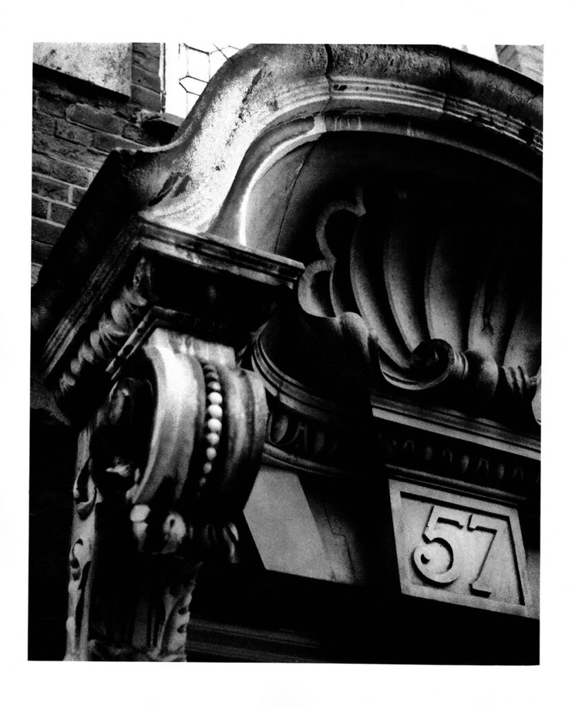 An analogue black and white picture of an entrance to the building number 57.